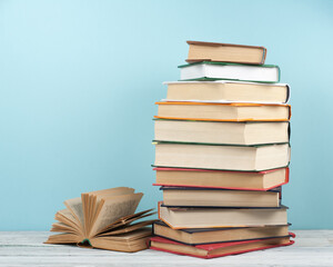 Sticker - Open stacking book, hardback colorful books on wooden table and blue background. Back to school. Copy space for text. Education business concept.