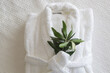White cotton bathrobe with olive tree twig on the bed  in hotel room. Tourism, hotels, hospitality industry