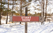 Start now symbol. Concept words Start now on beautiful wooden road sign. Beautiful forest snow blue sky background. Business marketing, motivational start now concept. Copy space.