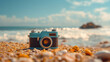 A vintage camera placed on a pebbly beach with the ocean in the background