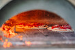 Dobele, Latvia - August 18, 2023 - Pizzas baking in a wood-fired oven with glowing embers.