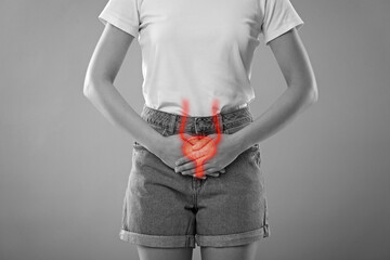 Poster - Woman suffering from cystitis on light grey background, closeup. Illustration of urinary system