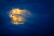 Striking image capturing a single cloud, brightly lit by sunlight against a dark twilight sky. This scene evokes feelings of hope and isolation.
