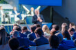 Blurred view of a business speaker engaging with a professional audience at a conference. Focus on informative interaction and networking opportunities.