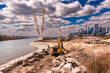 heavy machinery reshaping a river mouth with a city skyline, white clouds and blue sky in background room for text shot toronto portlands development