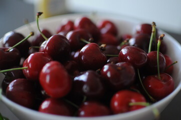 Fresh ripe organic berry red sweet cherries on plate on a dark stone tabletop. Food from above.