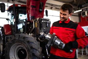 Poster - Professional mechanic repairing tractor transmission inside workshop.