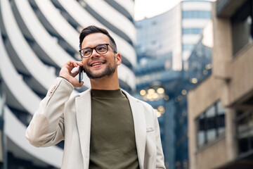 Handsome confident business professional talking on a phone outside.