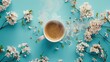 A white mug filled with steaming hot coffee rests on a vibrant blue backdrop adorned with delicate flowers captured in a breathtaking flat lay from a top down angle