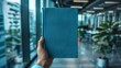 A blank blue book cover is displayed on a modern office background.