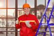 Portrait of smiling elder man with dollar baknotes showing like gesture. Handyman construction worker with his salary standing indoors.