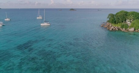 Poster - A aerial beautiful blue ocean with a few boats floating on it. The boats are small and are scattered throughout the water. The scene is peaceful and serene, with the boats adding a sense of leisure