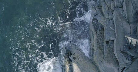 Poster - A rocky shoreline with a body of water in the background. The rocks are scattered across the shoreline, and the water is calm and blue. The scene is peaceful and serene