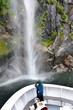 People on the boat near spectacular waterfall, Milford Sound fiordland , New Zealand