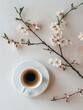 A shot of a cup of black coffee with a small vase of flowers.