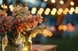 A garden party setup under string lights, with tables adorned with vases of Cymbidium orchids