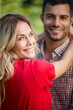 © peopleimages.com - Portrait, couple and hug with smile in nature for bonding, love and relationship outdoors. Happy, woman and man embrace in summer holiday for travel, date or romance together in the park or forest