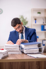 Wall Mural - Young male employee and too much work in the office