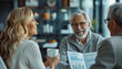 © Vadim - Cheerful senior man and his wife discussing investment plans with financial advisor while sitting in cafe.