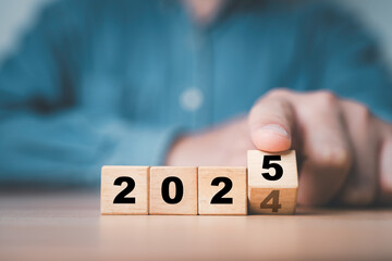 Wall Mural - businessman flipping of 2024 to 2025 on wooden block cube for preparation new year change and start 