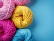 Colourful yarn balls on a soft blue background for crafts.
