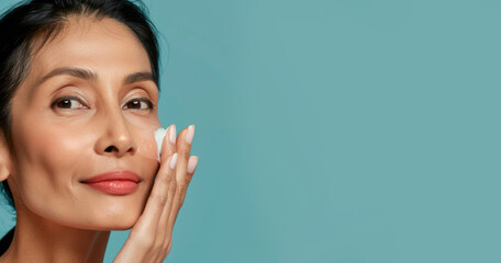 A middle-aged Asian woman with radiant, glowing skin applying a facial serum