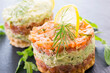 Gourmet salmon fish fruit tartar raw from salmon fillet with chopped avovado as close-up on a black design board