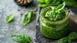 Fresh pesto sauce in a jar on a gray stone background
