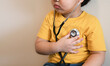 fat kid put yellow tight shirt listens to the lungs and heart with medical stethoscope. hospital life insurance concept, World heart health day, doctor day, world hypertension day.