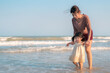 Asian mother holding hand daughter for support and walking on beach, Baby girl learning to walk, Happy family activity concept.
