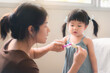 Asian mother and daughter brushing their teeth together, Mom teaching his daughter how to brush teeth, Oral health concept