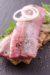 Traditional matie herring with onion rings served as close-up on a rustic wholemeal crispbread