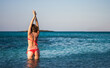 girl in red bikini practices yoga and Tai Chi in the sea water