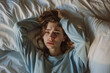 © Helena GARCIA - Mujer joven con cara de sufrimiento tumbada sobre una cama agarrándose la cabeza con sus manos sufriendo insomnio