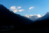 Fototapeta  - Darkened fields and mountain peaks still shining with sunlight