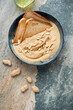 Bowl of peanut butter with toasted bread, vertical shot on a beige and grey granite background, flat lay with space