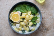 Potato gnocchi with spinach and feta in a grey bowl, horizontal shot on a beige granite background, high angle view