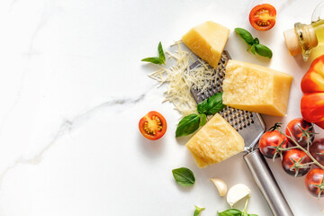 Poster - Italian food cooking ingredients background with fresh cherry tomatoes, basil leaves, herbs, garlic, olive oil and parmesan cheese on white stone table with copy space top view. Healthy eating