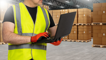 Poster - Man warehouse supervisor. Logistician with laptop in hands. Cropped supervisor near pallets with boxes. Man worker in warehouse building. Supervisor stands in hangar for logistics center
