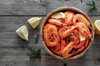 Fresh fried shrimps in a wooden bowl with lemon slices on a wood background top view