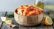 Fresh fried shrimps in a wooden bowl with lemon slices on a wood background close up