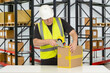 Man warehouse packer. Worker with box and tape dispenser. Packer near racks for boxes. Warehouse contractor wearing reflective vest. Warehouse packer career. Man storekeeper in white hardhat