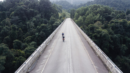 Aerial view of motorcycles on the elevated road across the rainforest mountains in Hulu Selangor, Malaysia.