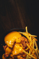 Wall Mural - top view of crispy chicken bits with cheddar sauce and french fries
