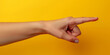woman's hand pointing to the right with the index finger on an isolated yellow background, shopping discounts concept