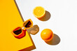 Minimal style composition made of trendy sunglasses and orange fruit on sunlit geometric background