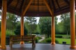 A gazebo with a wooden bench and large windows overlooking a lush green forest.