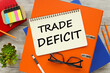 TRADE DEFICIT Top view of empty notepad and various office supplies on wooden table