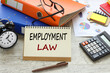 Employment law text concept on sheet with notepad and calculator.