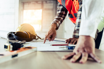 Wall Mural - Close up hands of businessman from consultancy service discussing with project contractor and reviewing blueprint for build real estate facilities.